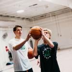 A coach showing a teen a basketball skill.