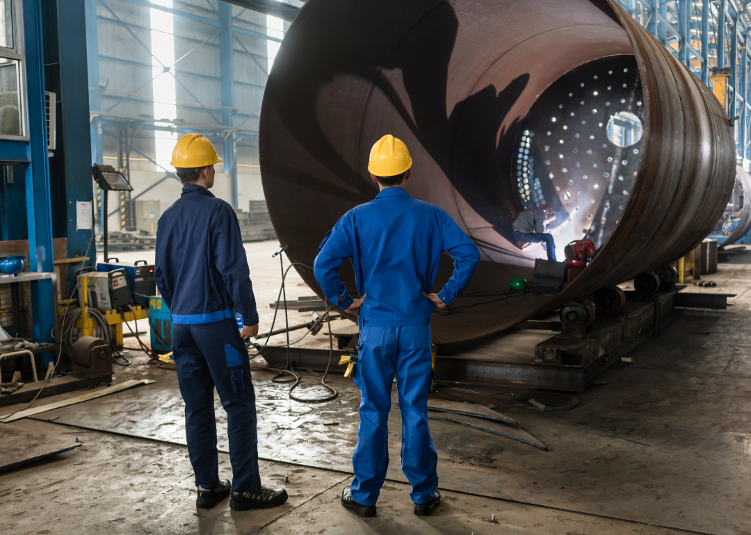 Workers supervising the manufacture of heavy equipment