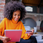 Young Black woman with an iPad and a credit card in her hand.