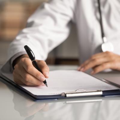 Doctor filling out paper medical records.