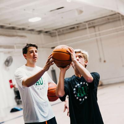 A coach showing a teen a basketball skill.