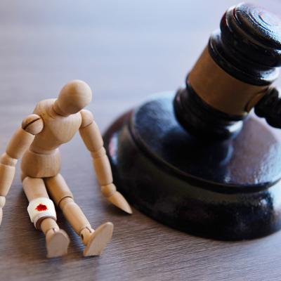 A judge gavel beside a wooden injured figure as a concept of personal injury law.